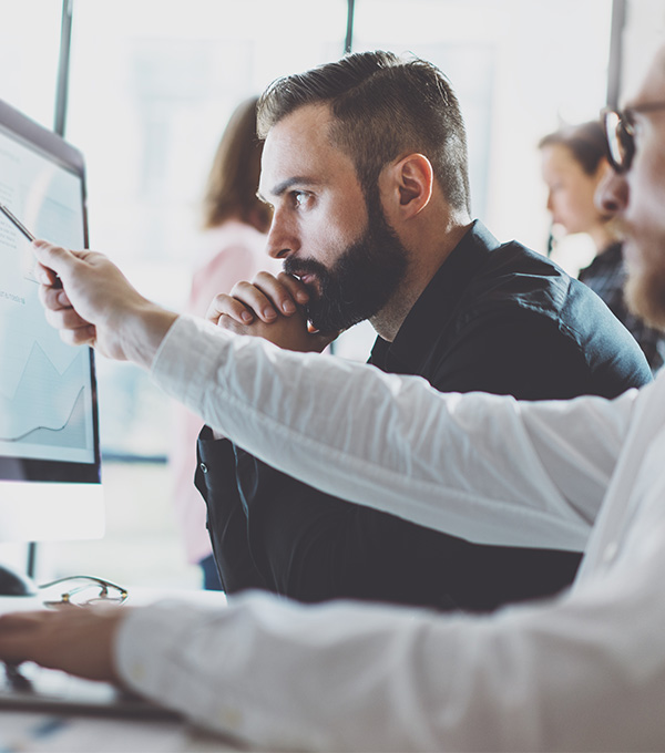 Man-wijst-iets-aan-op-beeldscherm-voor-serieus-kijkende-collega
