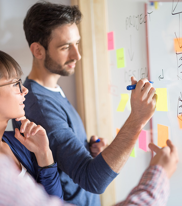 Vrouw-en-man-tekenen-processen-op-raam-met-postits