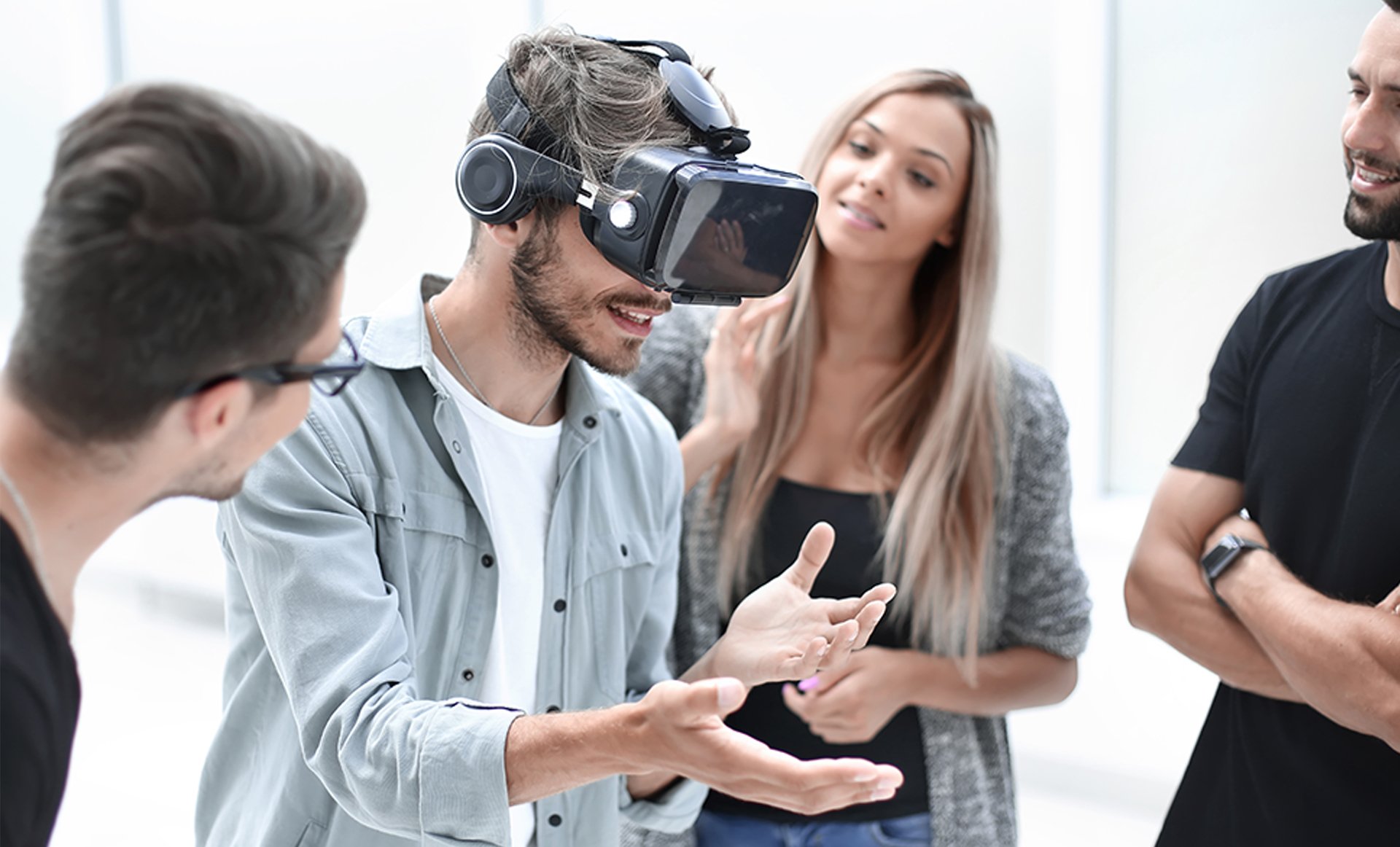 Man speelt met VR-bril terwijl enthousiaste collega's toekijken.