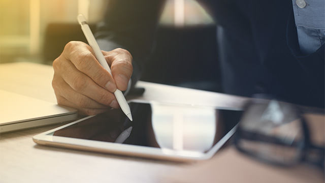 Man met stylus ondertekent document op tablet