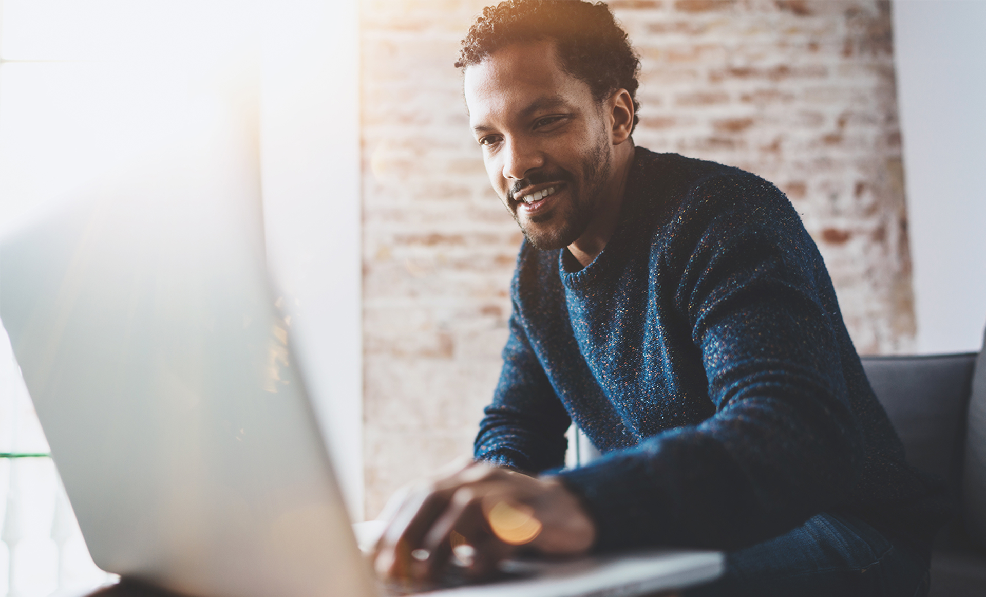 Man achter laptop, glimlachend in een meeting met externen