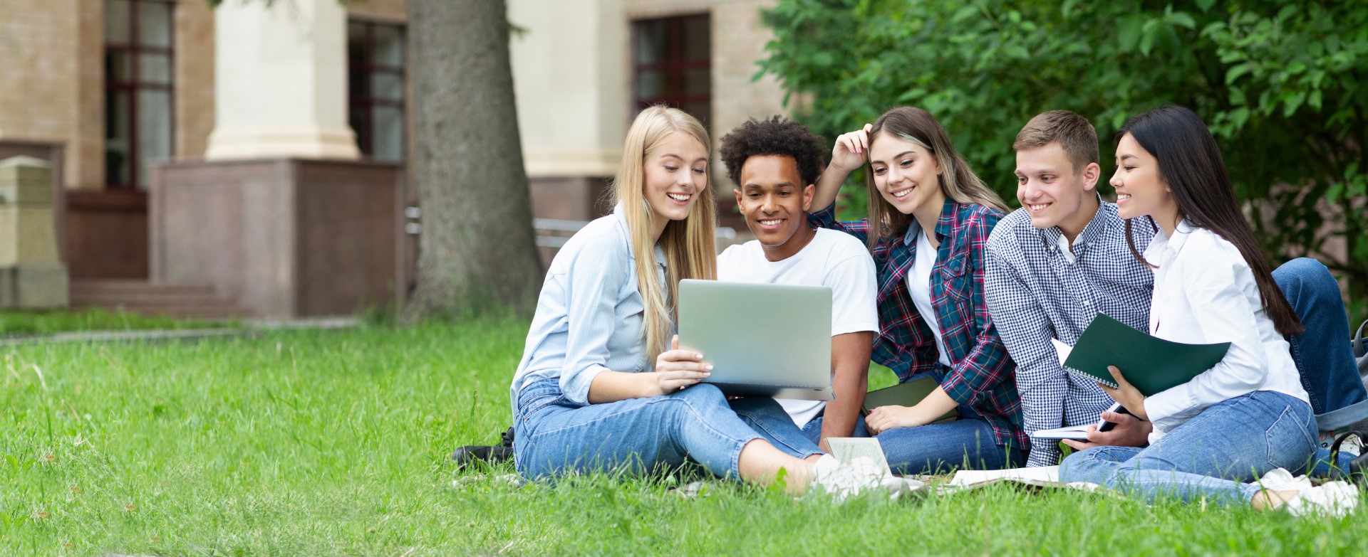 Studenten in een grasveld met laptop op schoot